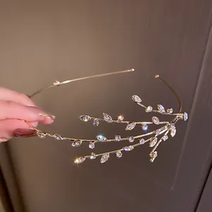 Detailed view of elegant gold vine headband decorated with sparkling rhinestone leaf accents