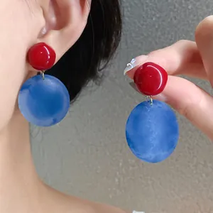 Vista dettagliata degli orecchini a perno geometrici in acrilico rosso e blu per donne