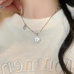 Primo piano di una collana color argento con ciondoli a cuore e fiore su una modella