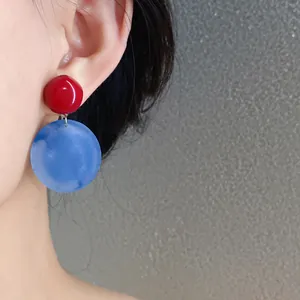Primo piano di eleganti orecchini tondi in acrilico rosso e blu indossati