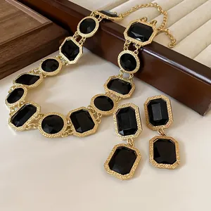 Nahaufnahme eines goldenen Vintage-Schmucksets mit schwarzen rechteckigen Kristallen.