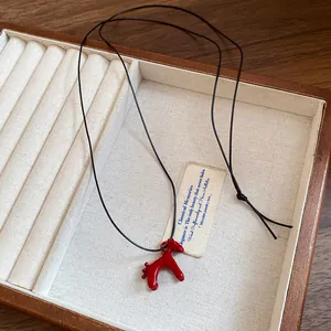 Vue détaillée du pendentif cheval en émail rouge dans une boîte à bijoux en bois