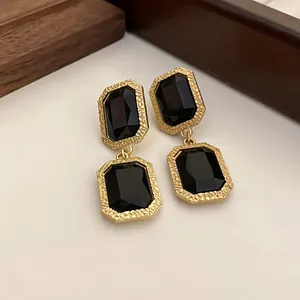 Nahaufnahme von Vintage-Ohrringen in Gold mit facettierten schwarzen Kristallen.