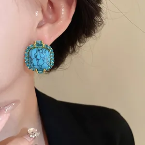 Vintage square turquoise stud earrings with blue crystal halo shown on model's ear