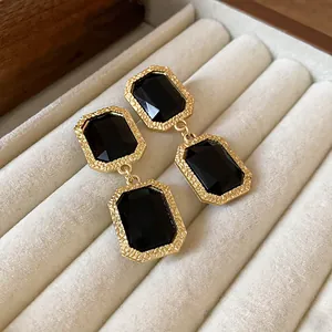 Nahaufnahme von schwarzen Vintage-Kristallohrringen mit goldenem Rahmen in einer Box