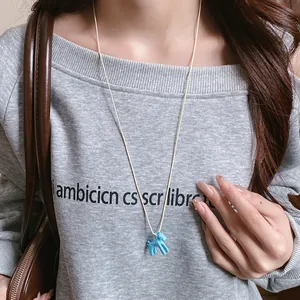 Gros plan détaillé d'un collier avec pendentif poney bleu porté sur un sweat-shirt gris