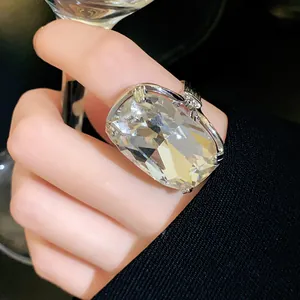 Detailed close-up of a large cushion-cut crystal ring in a silver setting worn on finger.