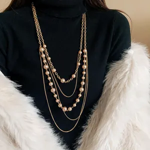 Vista detallada de un collar de suéter vintage de varias capas con perlas y cadena