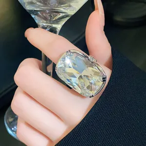 Close-up of exaggerated rectangular crystal ring with silver setting on finger