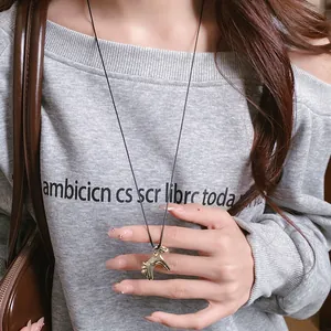 Gros plan d'un collier pendentif cheval vintage doré porté sur un pull gris chic