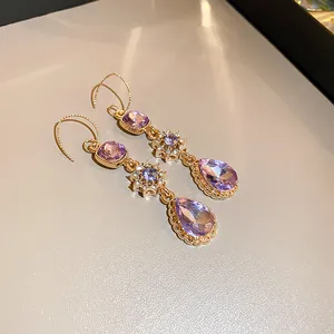 Detail view of vintage gold teardrop earrings with purple and blue zircon stones.
