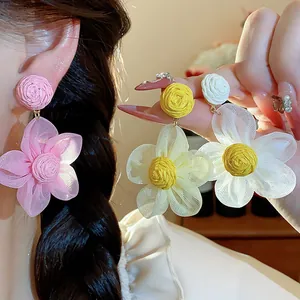 Detailed view of handmade raffia and chiffon flower earrings in sweet pastel colors