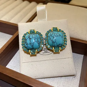 Close-up detail of vintage gold stud earrings featuring turquoise stone and teal rhinestones