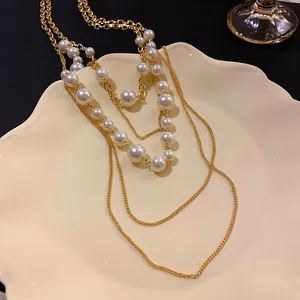 Primer plano de un collar vintage de cadenas doradas con elegantes perlas de vidrio blancas