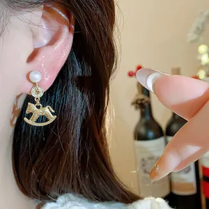 Detailaufnahme eleganter 18K Goldohrringe mit Schaukelpferd, Perle und Zirkonia
