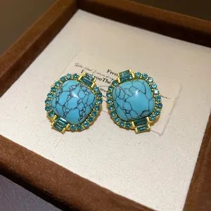 Close-up of vintage gold stud earrings with blue faux turquoise and crystal borders