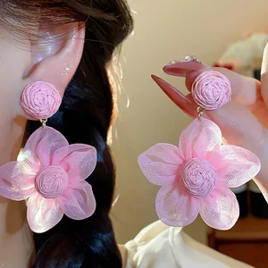 Close-up detail of elegant pink chiffon flower earrings with textured raffia centers