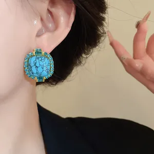 Detail shot of vintage faux turquoise stud earring with blue crystal halo on ear