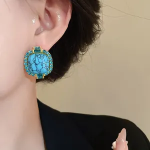 Detail shot of vintage turquoise stud earrings with blue crystal accents on ear
