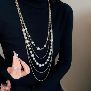Vista detallada de un collar de cadena dorada de varias capas con perlas blancas
