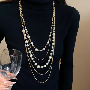Detalle de elegante collar de suéter multicapa con perlas sintéticas y cadena dorada