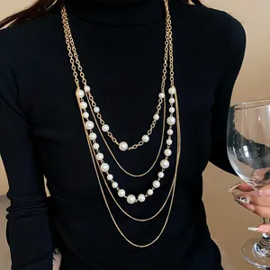 Primer plano de un collar vintage de varias capas en oro con perlas blancas de varios tamaños