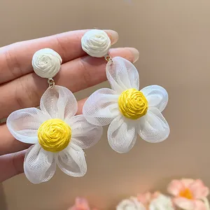 Close-up of chiffon flower earrings with textured yellow raffia center and silver needle