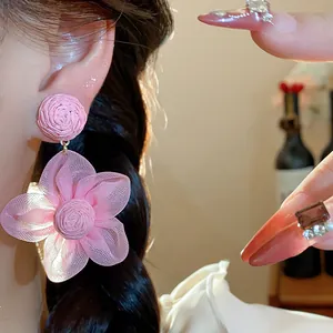 Close-up detail of sweet pink chiffon flower earrings with raffia studs worn on model