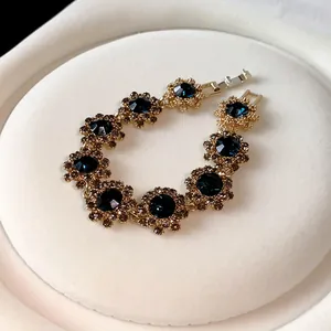 Nahaufnahme eines goldenen Armbands im Vintage-Stil mit dunkelblauen Kristallblumen.