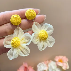 Close-up view of handmade raffia and chiffon flower earrings with delicate textures