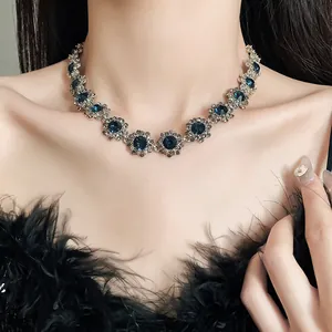 Detailansicht einer eleganten Blumenkette mit blauen Strasssteinen an einem Modell.