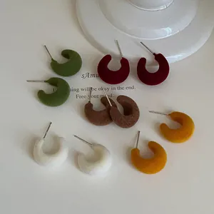 Close-up view of colorful flocked C-shaped stud earrings featuring a soft velvet texture
