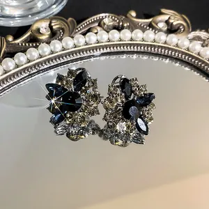 Close-up detail of vintage floral stud earrings with blue and champagne rhinestones.