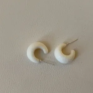 Detail shot of white flocking C-shaped stud earrings with silver pins for women