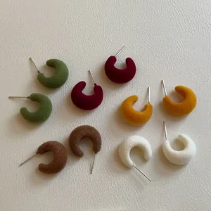 Collection of flocked C-shaped stud earrings in various autumn colors with silver pins
