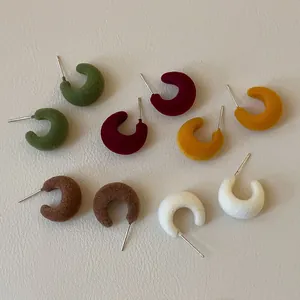 Detailed view of minimalist flocked C-shaped stud earrings in various autumn colors.