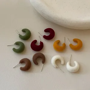Macro detail of C-shaped flocked stud earrings in various autumn colors with silver needles