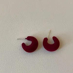 Detailed close-up view of burgundy flocking C-shaped stud earrings with velvet texture