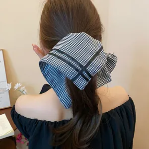 Detail view of a black and white gingham checkered scarf hair tie on a low ponytail.