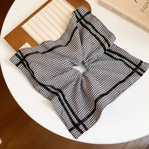 Detailed view of square checkered hair scrunchie with elegant black ribbon accents