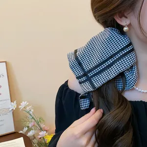 Detail shot of a black and white gingham scrunchie used on a woman's brown ponytail.
