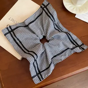 Detailed view of a black and white checkered square hair scrunchie with elegant ribbon trim