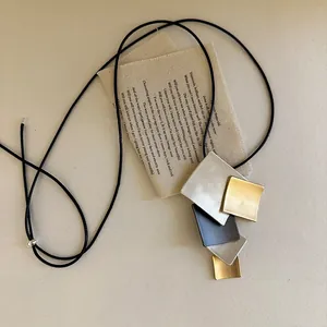 Close-up detail of a geometric metal pendant necklace with multi-color square elements