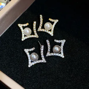 Detailed close-up of geometric rhinestone stud earrings with elegant white and grey pearls.