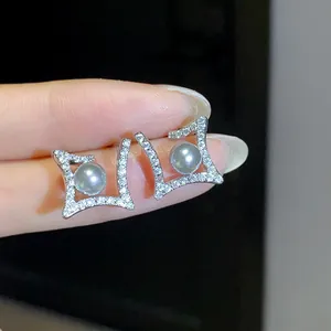 Detailed view of silver-tone geometric stud earrings with pavé stones and grey pearls.