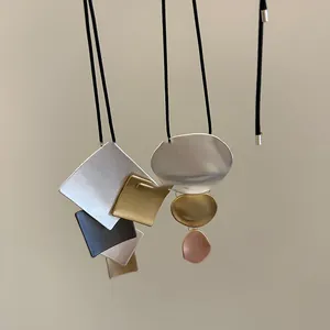Detailed view of minimalist metal geometric pendant necklaces on black cords