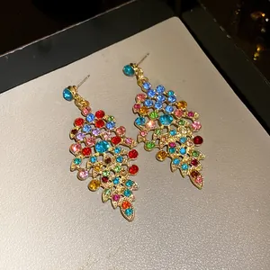 Close-up of vintage-style gold earrings with vibrant multi-colored rhinestone leaf design.