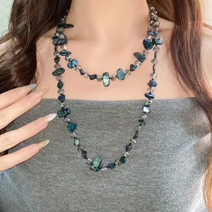 Détail d'un long collier de perles en nacre irrégulière et verre facetté style rétro