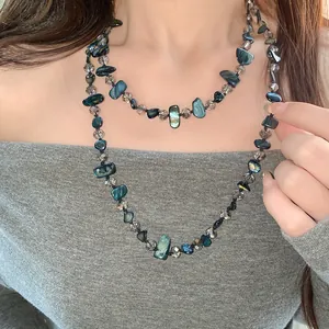 Détail d'un collier vintage avec des coquillages irréguliers et des perles en verre.