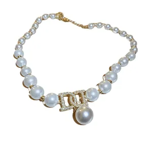 Elegant white pearl necklace featuring a sparkling gold-tone CD logo rhinestone pendant